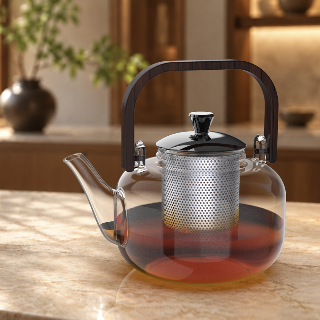 Glass teapot with a metal infuser and dark handle on a warmly lit countertop